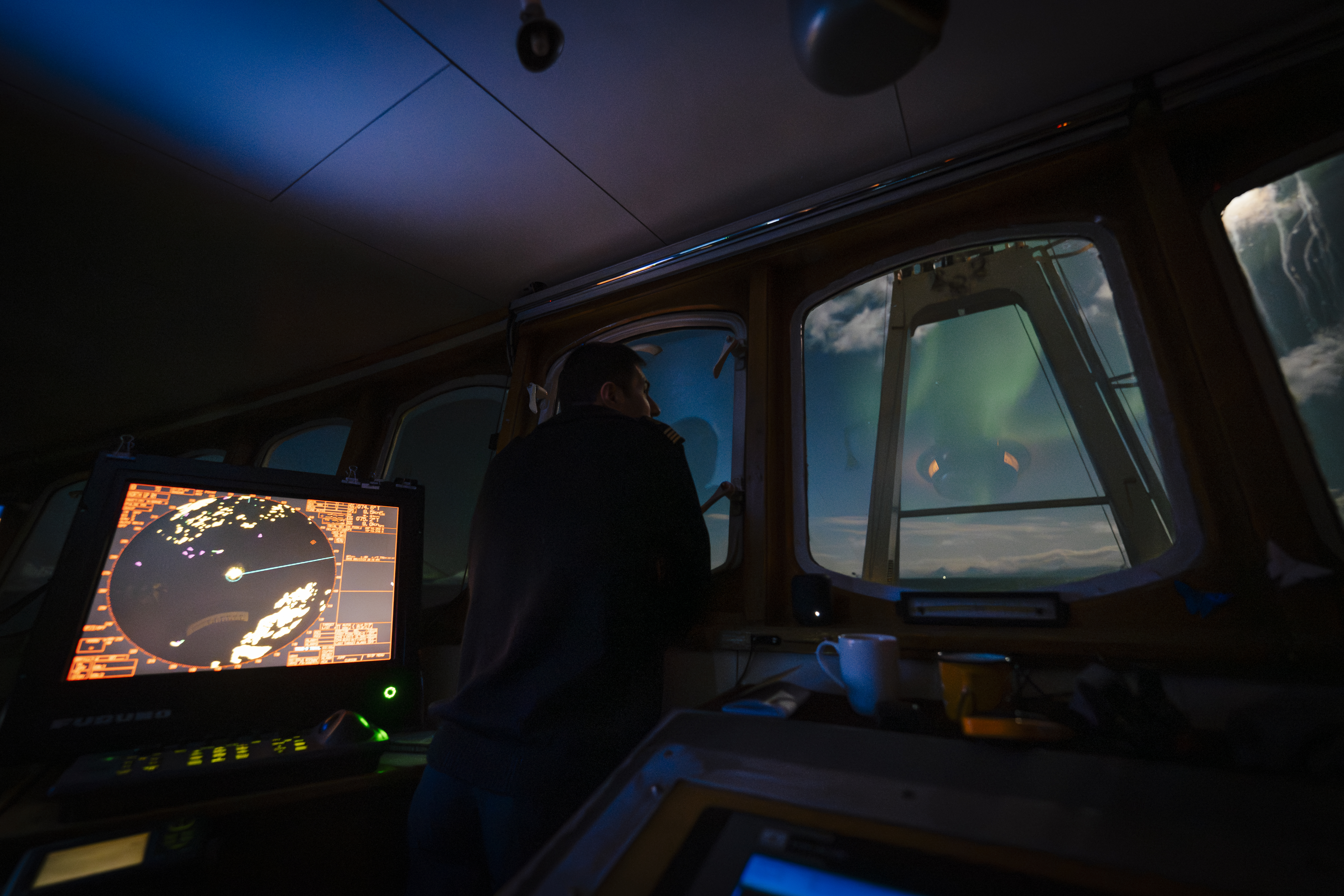 Polarfront’s bridge at night, the radar screen glowing and the northern lights beyond the windows