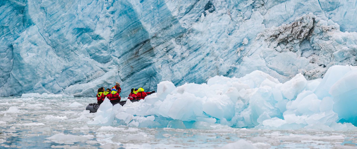 Guests in a Zodiac at the foot of a glacier front