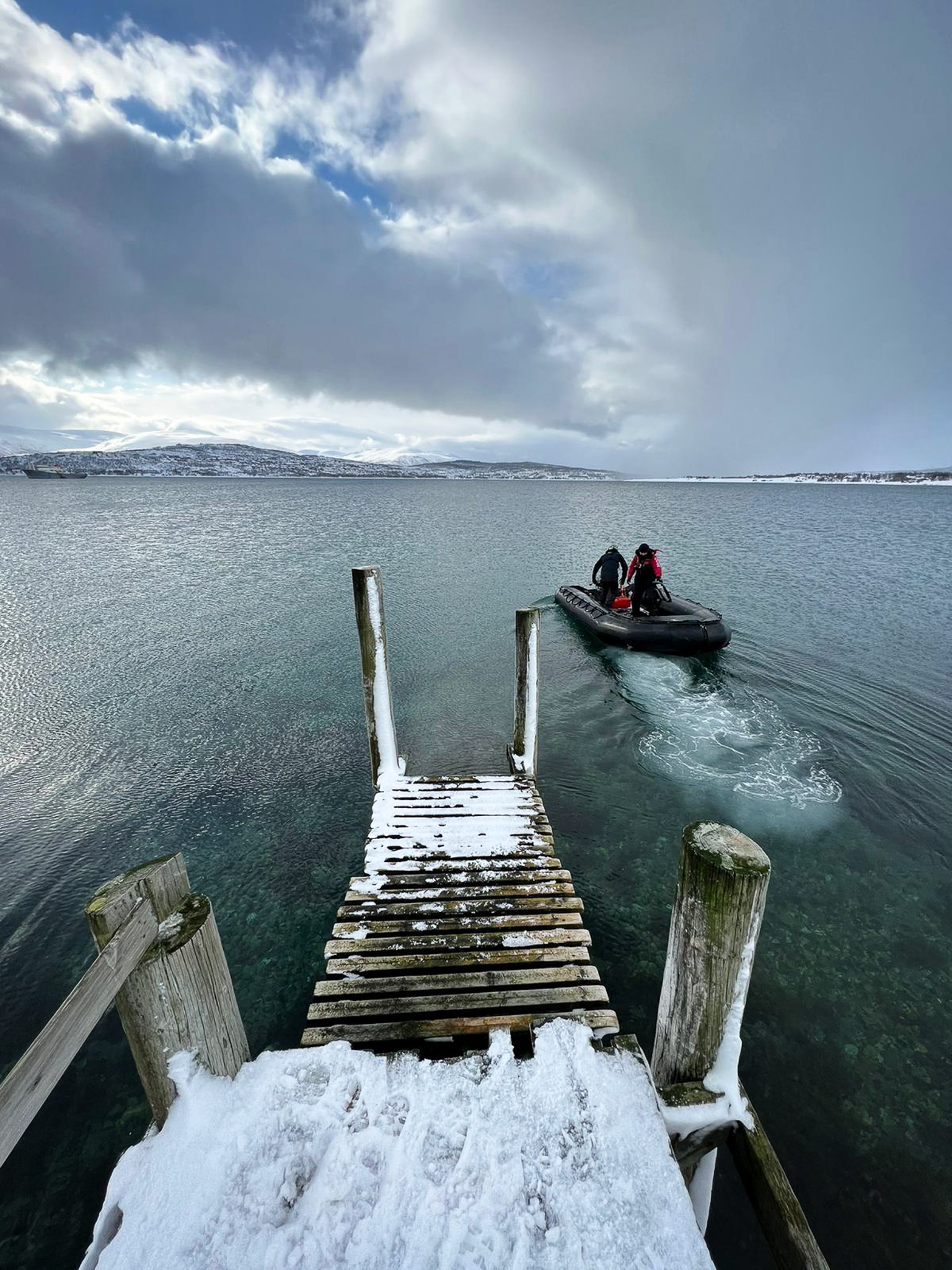 A Zodiac pulls away from a snowy dock in Norway